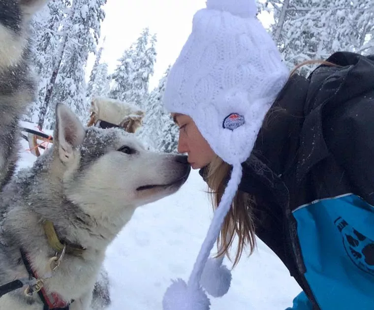 Jeune fille embrassant un chien de traineau en Laponie