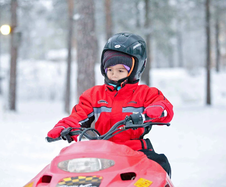 Petit garçon conduisant une mini-motoneige en Laponie