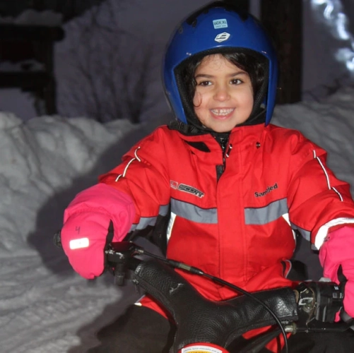 Petite fille souriante conduisant une mini-motoneige à Noël à Harriniva