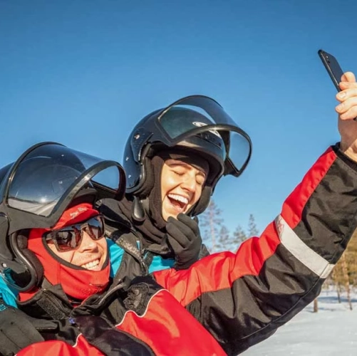 Couple en motoneige prenant un selfie avant d'atteindre le SnowVillage