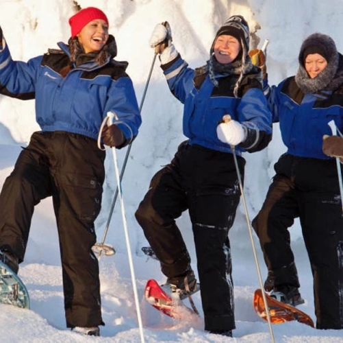 Trois amies en raquettes, complices et pleines d’entrain, explorent la forêt immaculée dans les éclats de rire