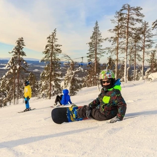 Petit snowboardeur posé sur la piste