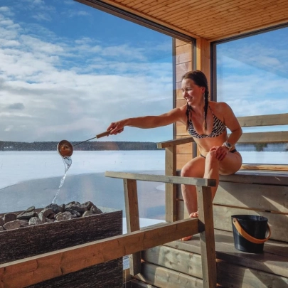 Femme assise dans l'un des saunas en bois traditionnel du centre Arctic Sauna World, au bord de l'avanto du lac Jerisjärvi