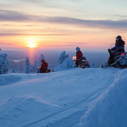 Motoneiges traversant la neige immaculée sur un sommet enneigé au lever du soleil à Muonio