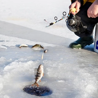 Participant assis sur un seau pratiquant la pêche blanche sur un lac gelé à Muonio