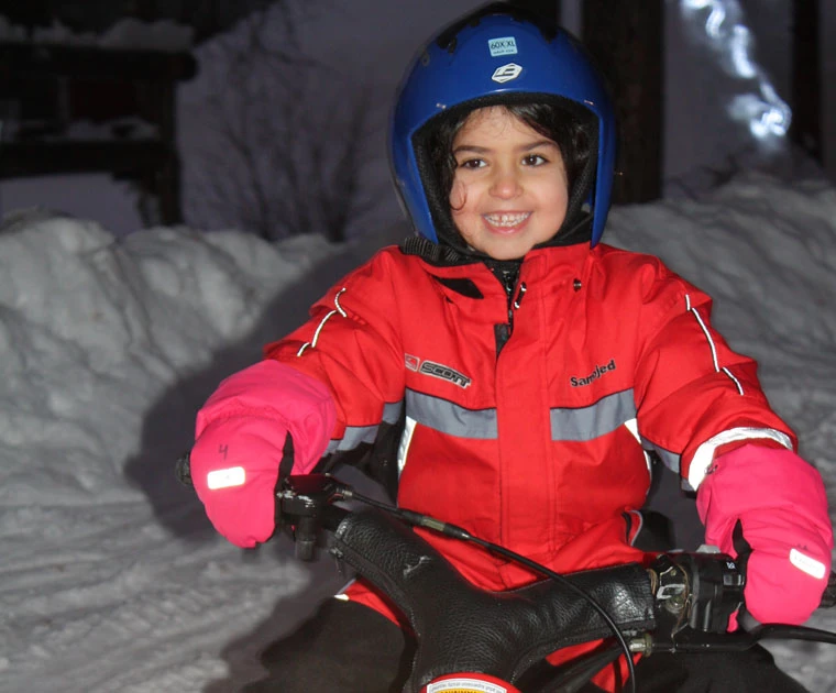 Petite fille souriante conduisant une mini-motoneige à Noël à Harriniva