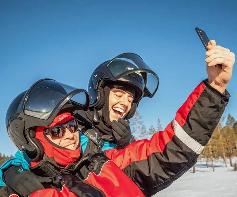 Couple en motoneige prenant un selfie en Laponie