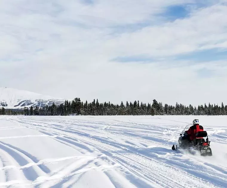 Motoneige sur un lac en direction d'une colline en Laponie