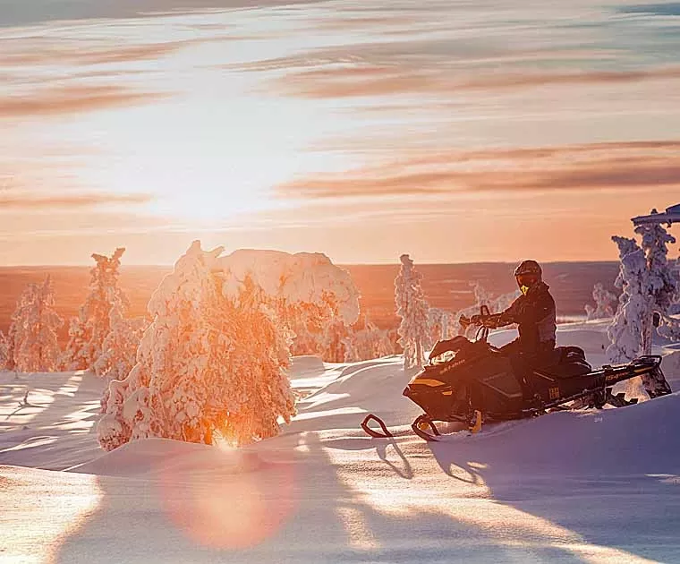 Motoneige vers Vuontis sous un ciel orange en Laponie