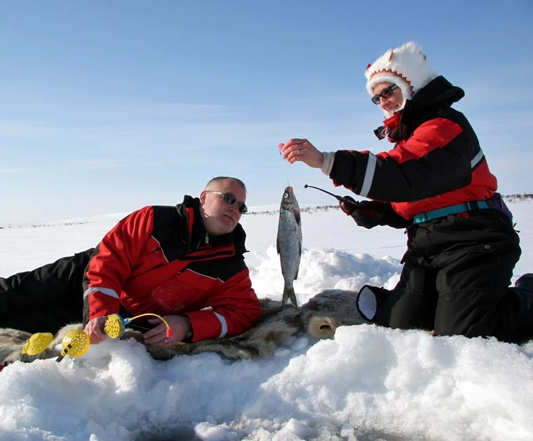 Un couple heureux d'avoir pêché un poisson sous la glace du lac