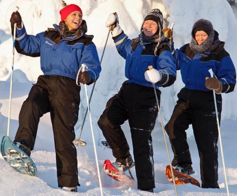 Trois amies en raquettes, complices et pleines d’entrain, explorent la forêt immaculée dans les éclats de rire