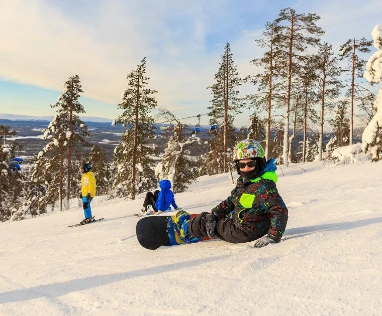 Petit snowboardeur posé sur la piste